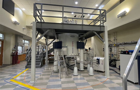 The first 1.2 GHz NMR Spectrometer in the U.S. installed at Ohio State University. The instrument is encircled by a raised platform and other instrumentation can be seen in the lab.