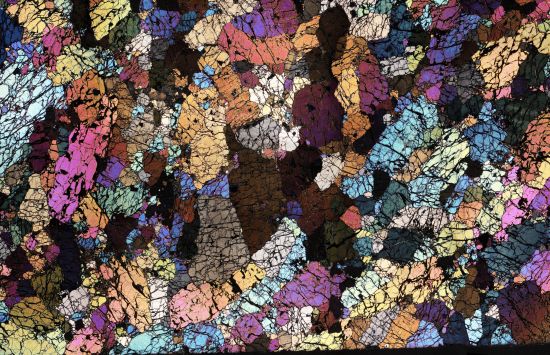 A mosaic-like picture with many colours showing a thin slice of rock under a microscope.