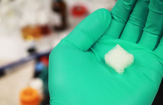 Closeup of a scientist holding a piece of square polymer foam