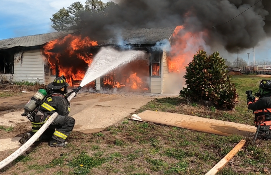 Firefighters using a HEN nozzle to extinguish a house fire.