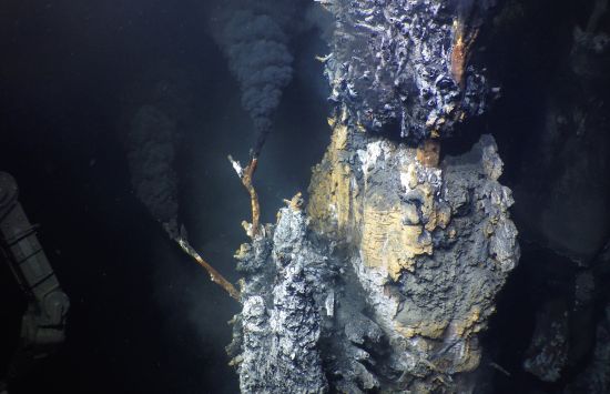 A deep sea vent emitting a dark cloud that resembles black smoke.
