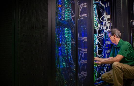 A man kneels to work on colorful wires.