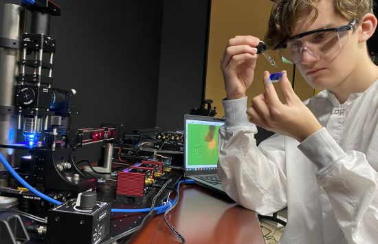 student in safety goggles preparing sample for quantum tweezers