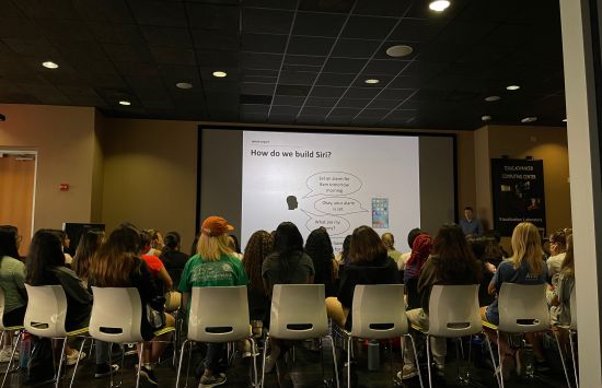 Students viewed from behind sitting in chairs watching a presentation.