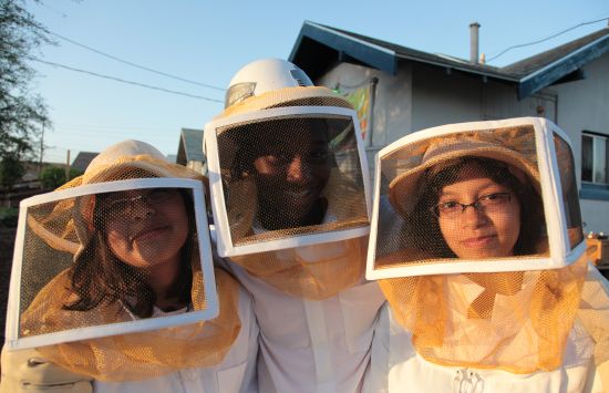 Three young women wearing beekeeping suits.