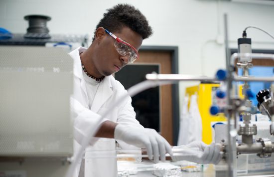 A student in a lab coat working in a laboratory.