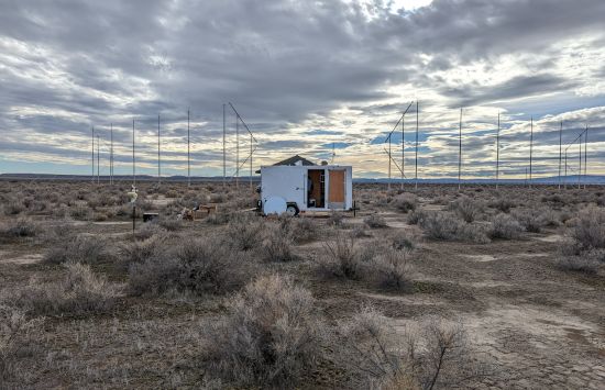 A white trailer with an open door in the middle of a dry field.