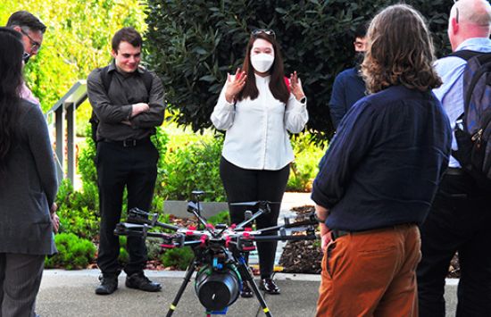 graduate students surrounding a drone