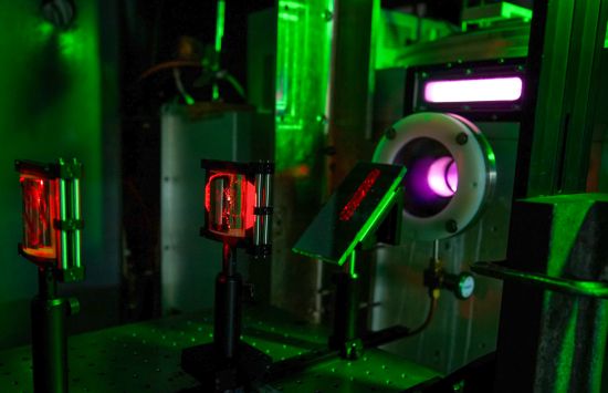 A laser table in a dark lab with red laser light visible and optical equipment.