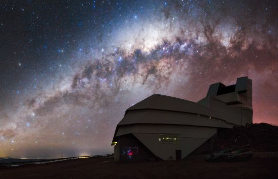 A ground view of an observatory with the Milky Way galaxy in the background.