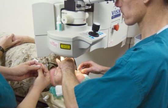 A surgeon looks through a microscope as they perform eye surgery on a patient.