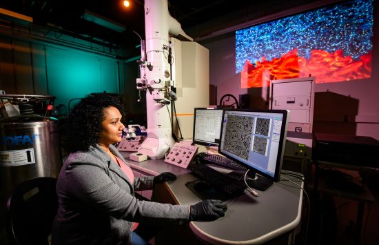 A researcher sits at a computer in a darkened lab.