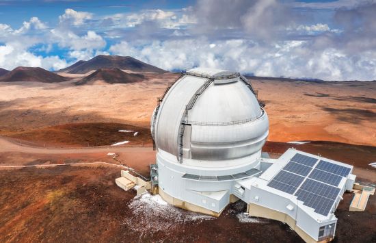 Gemini North Observatory at the summit of Maunakea in Hawaii with blue sky and clouds in the background.