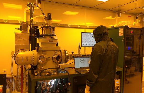 A researcher, wearing protective gear, standing in a glowing laboratory space.