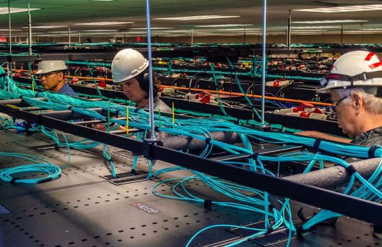 employees work on the network cabling above the racks of Frontera.