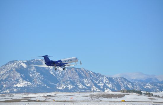 An aircraft taking off with snowy hills in the background.