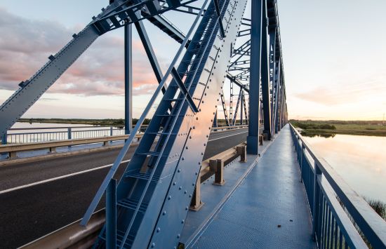 railway bridge with metal rails near river in sunset