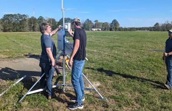 Researchers install solar-powered IoT tripod sensor system in farm field.