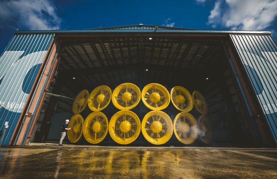 Twelve giant yellow fans inside a large warehouse.
