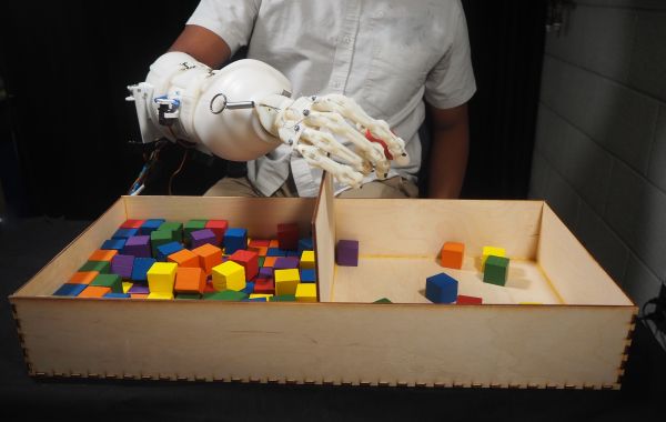 Wearable anthropomorphically driven prosthesis with built in haptic feedback system playing with colorful blocks