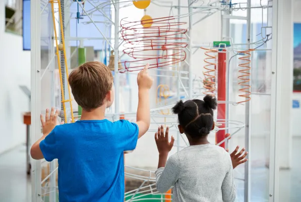 Two small children look at a colorful exhibit in a museum