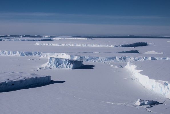 A flat snowy landscape is shown beneath a blue sky