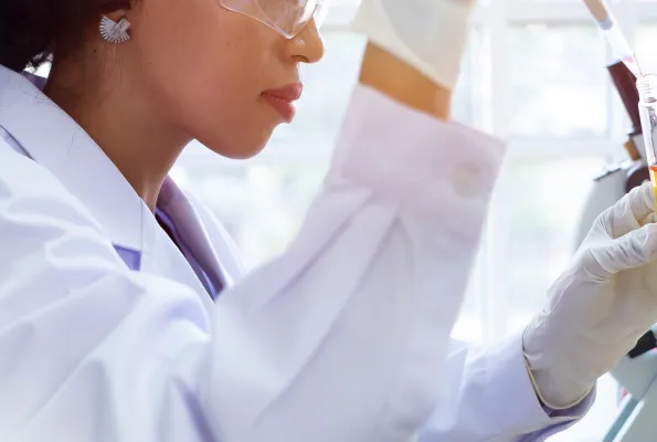 A cropped image of a woman in a lab coat using a pipette