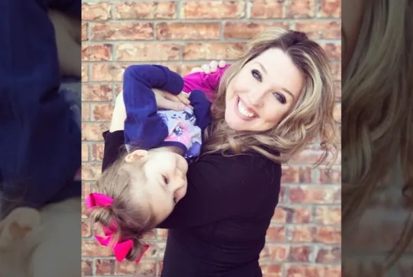 blonde female holding daughter with bow in her hair upside down