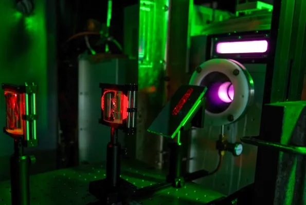 A laser table in a dark lab with red laser light visible and optical equipment.
