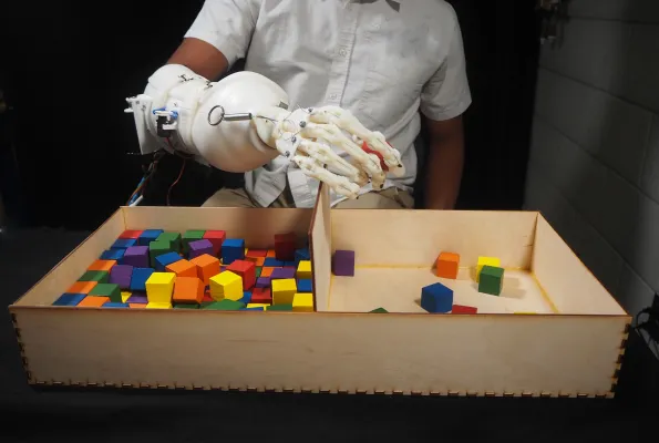 Wearable anthropomorphically driven prosthesis with built in haptic feedback system playing with colorful blocks