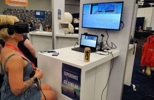 A woman explores NSF's Ice Cube through a virtual reality headset at an NSF event booth