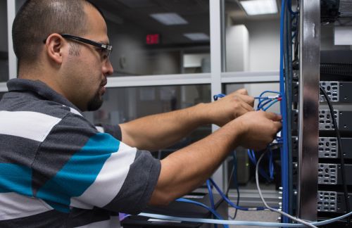 A student practices hands-on router configuration in a classroom convergence lab