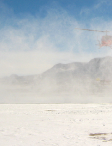 helicopter approaching two people in the snow