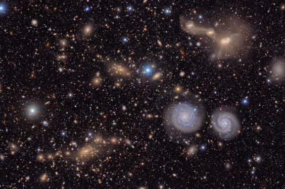 Many stars and galaxies including two spiral galaxies and three merging galaxies.