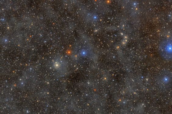 A dense field of colorful stars shining through a dust cloud