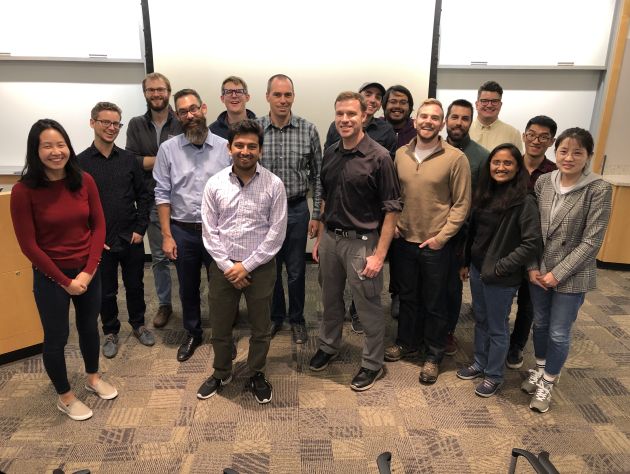 A group of people stand in a semicircle smiling