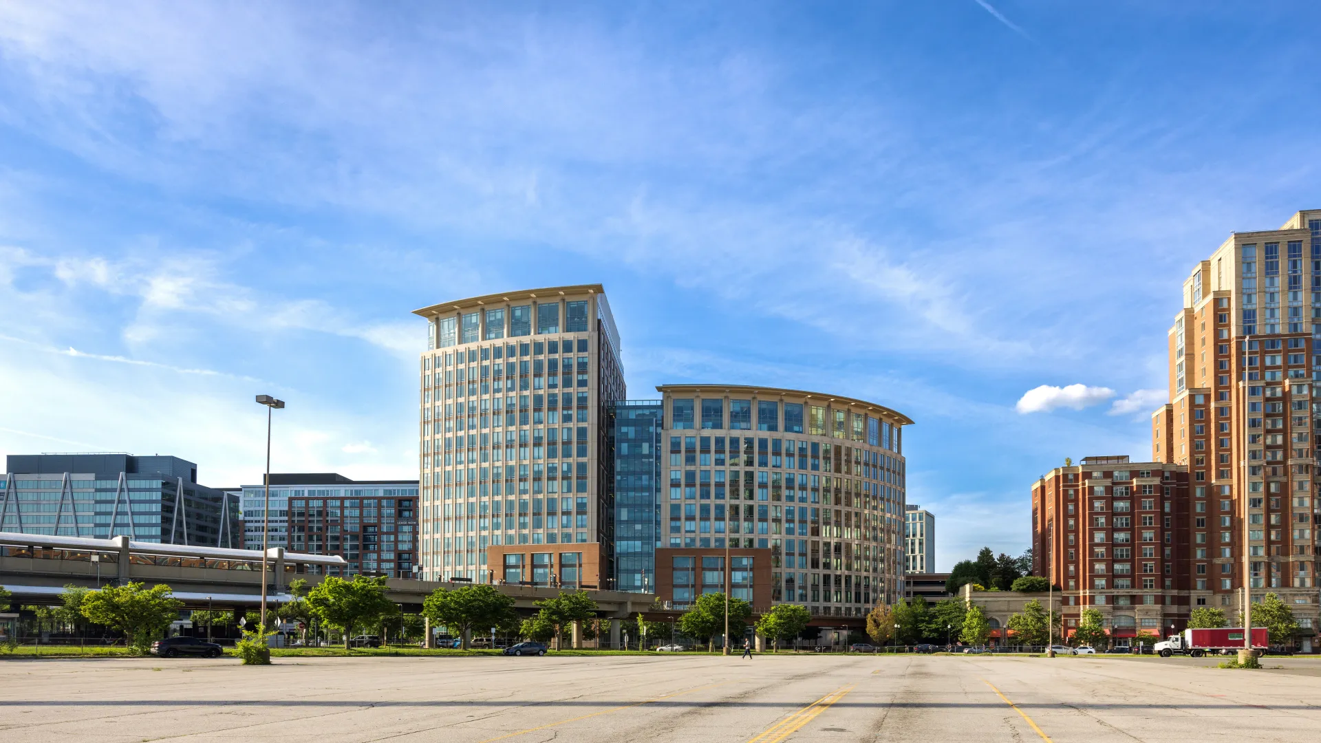 A Metro train sits parked at a station in front of a tall building.