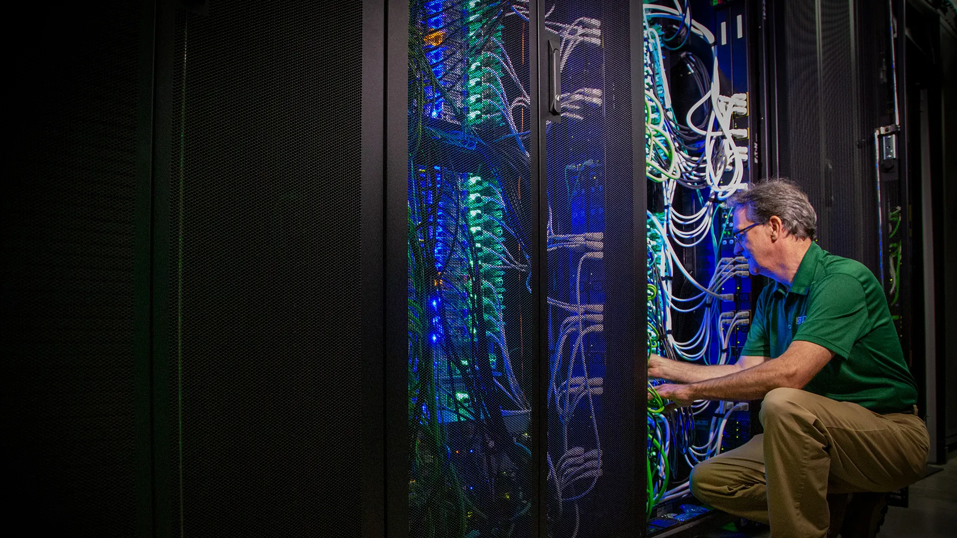 A man kneels to work on colorful wires.