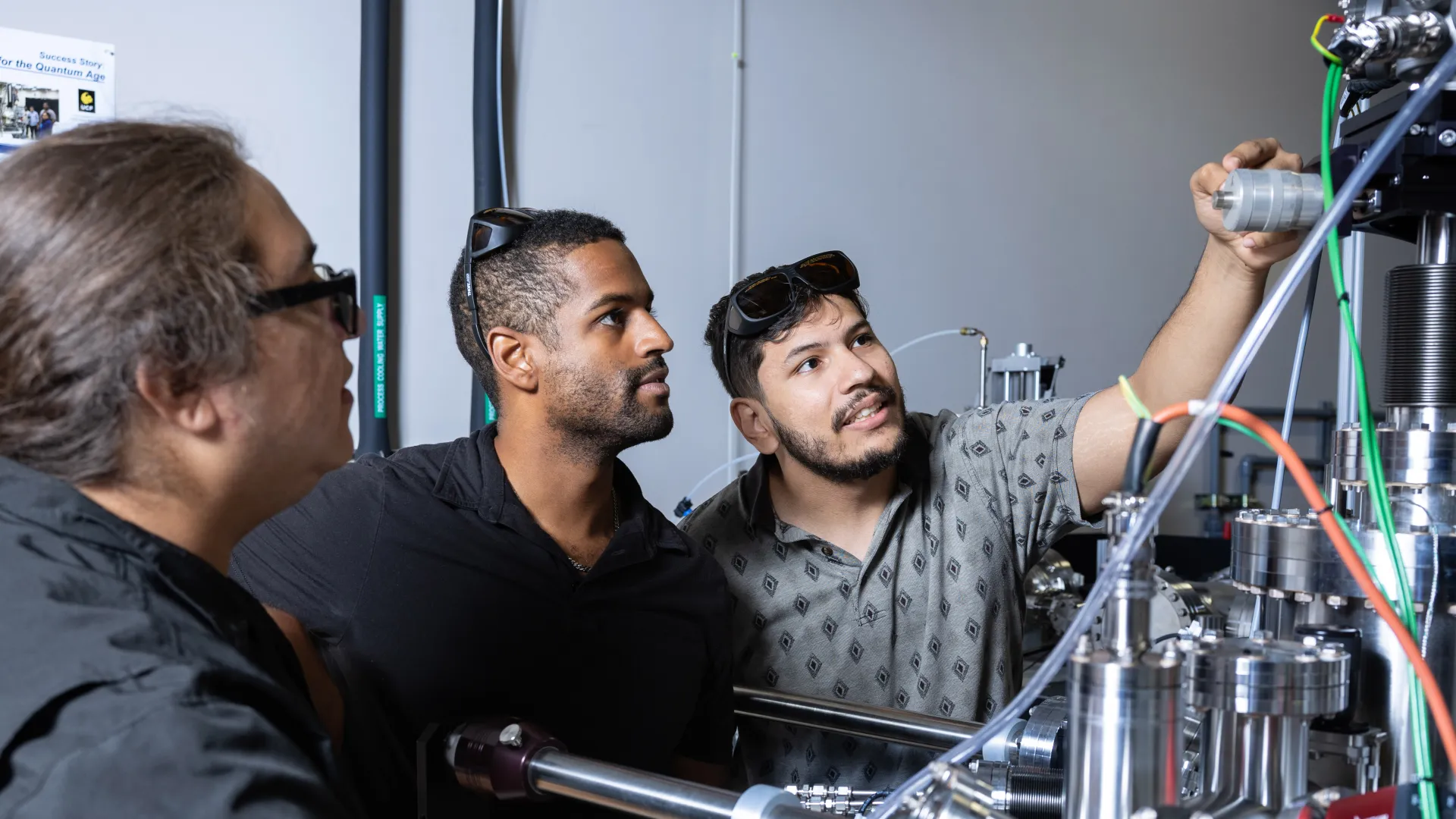 Three students adjusting experimental equipment.