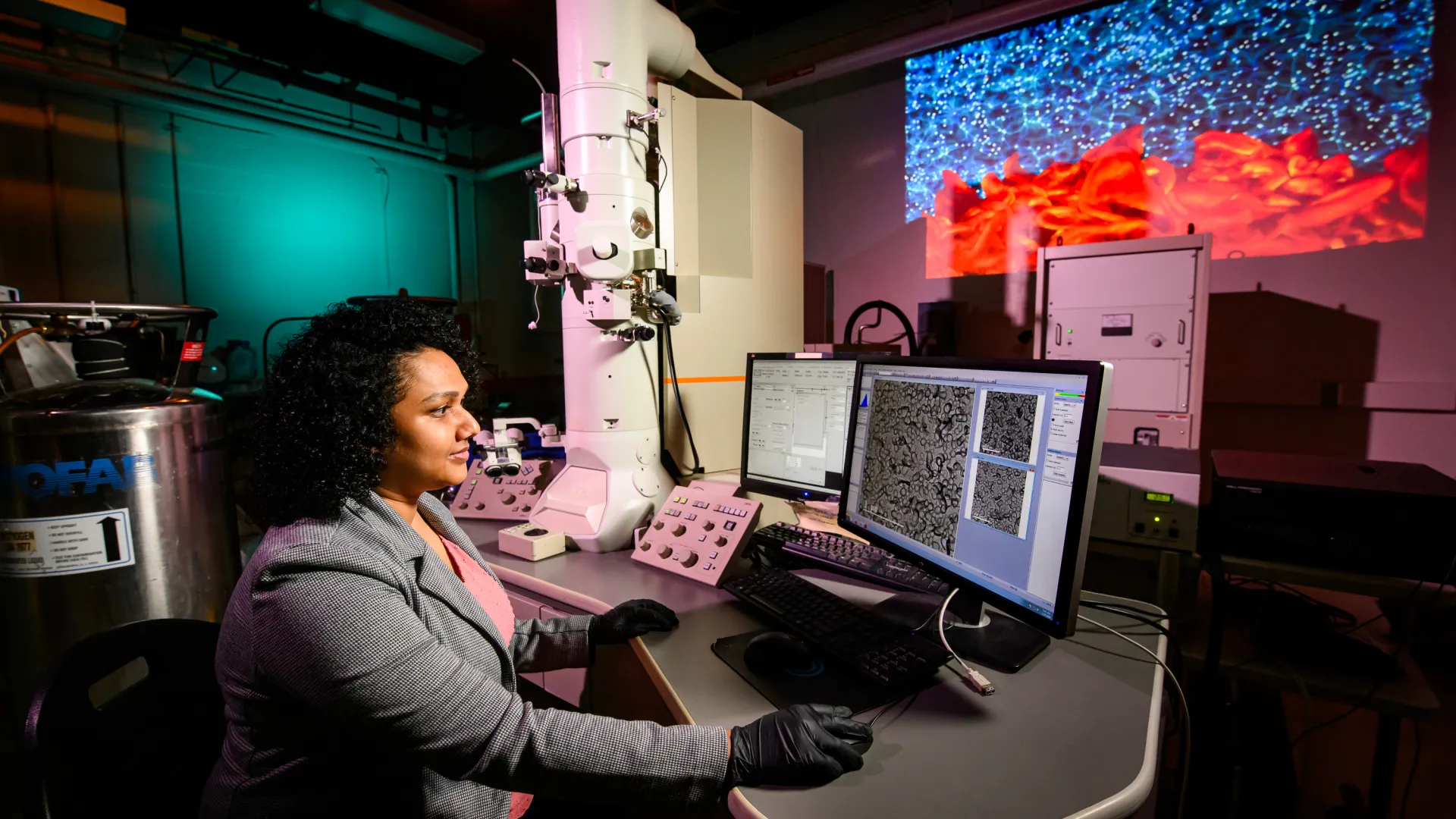 A researcher sits at a computer in a darkened lab.