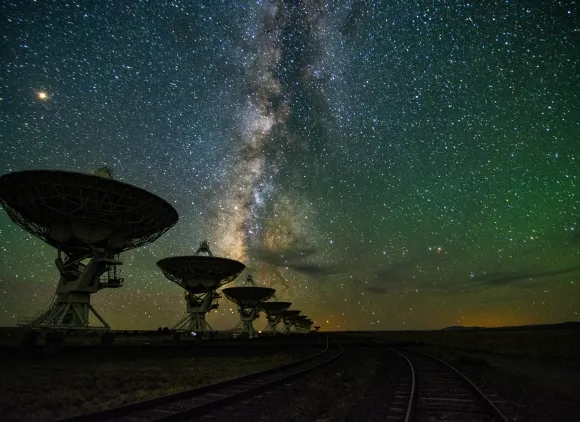 The Milky way galaxy is visible over radio telescopes at night