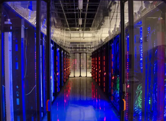 A dark hallway flanked by glowing walls of computers