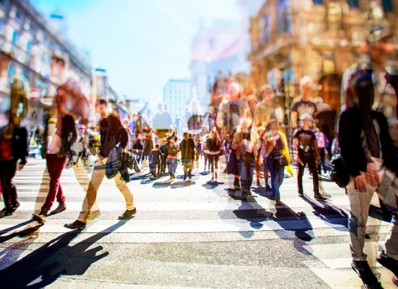 People walking on a crosswalk on a city street.