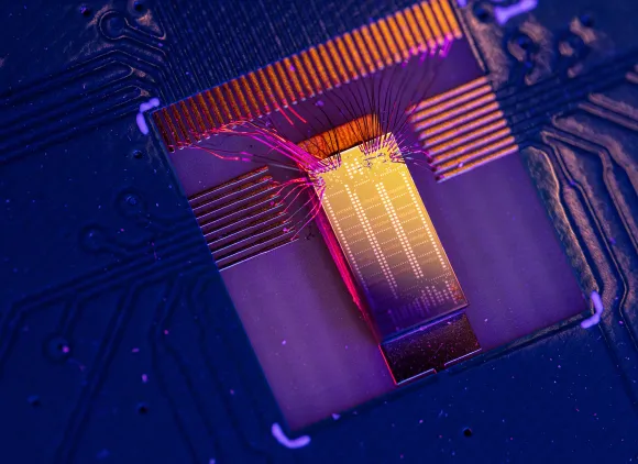 A purple microchip with a shiny yellow rectangle in the middle and orange ridges along the edges.