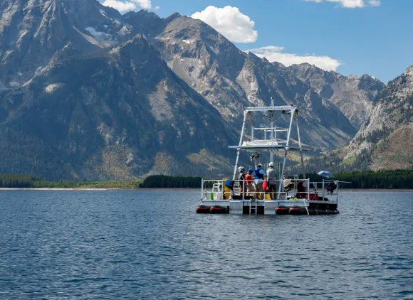 A boat in a body of water with a mountain background.