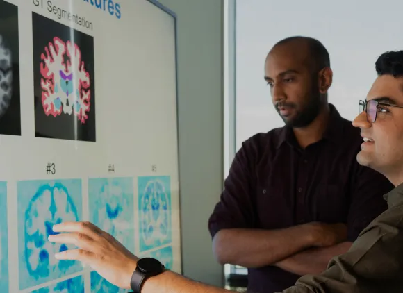 Two researchers examining images of brains projected on a white board.