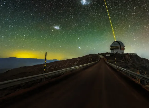 A domed observatory on a hill with a green, yellow and blue starry sky in the background.