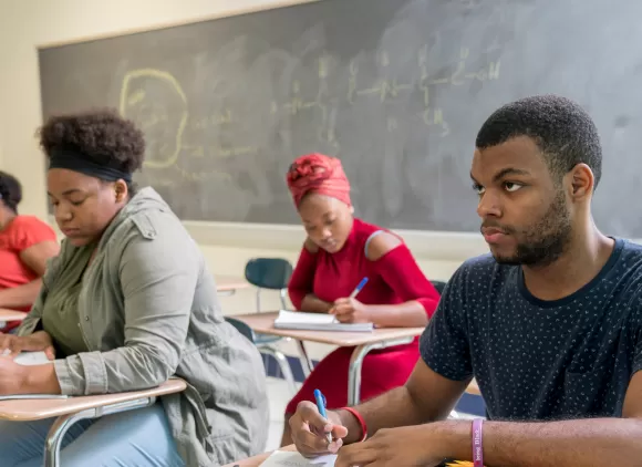 College students sitting at desks in a classroom.