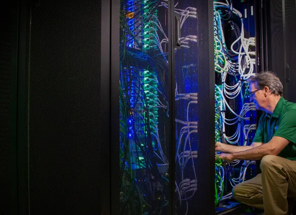 A man kneels to work on colorful wires.