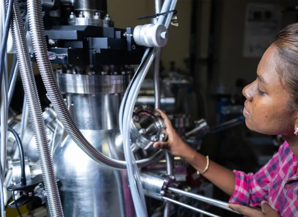 A student turns a knob on a large piece of metal equipment.